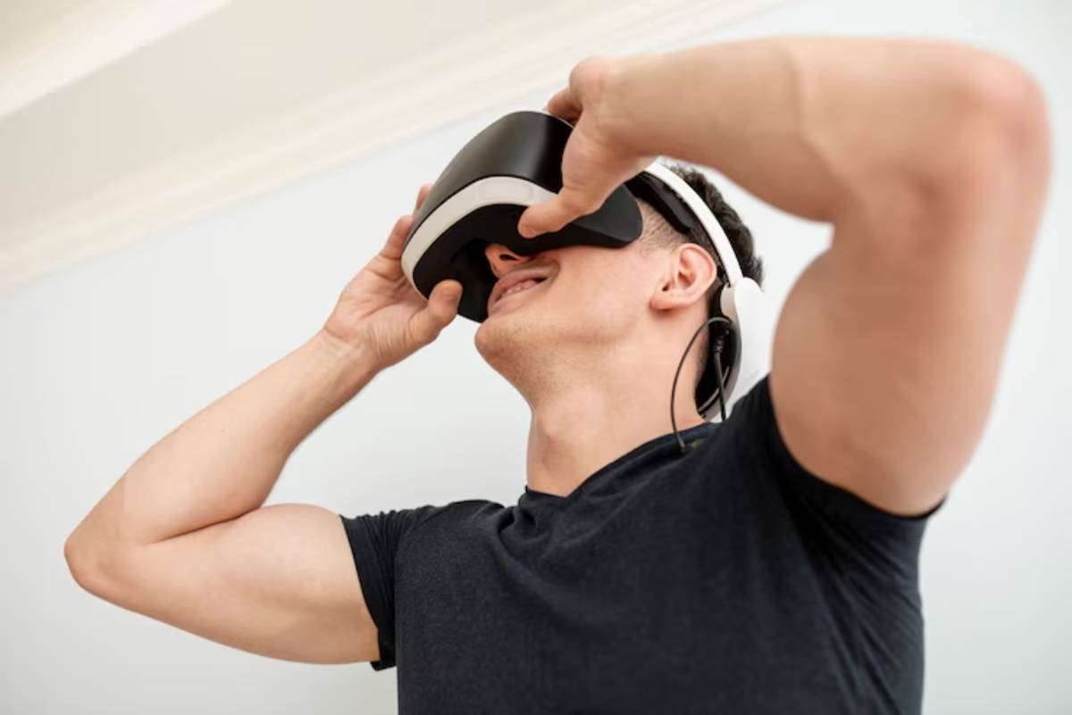A person with muscular arms adjusts a virtual reality headset, immersed in a digital experience in a bright, indoor setting.
