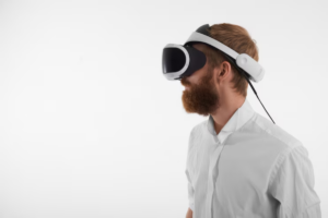 A person wearing a virtual reality headset and a white shirt, engaged in immersive technology against a plain white background.