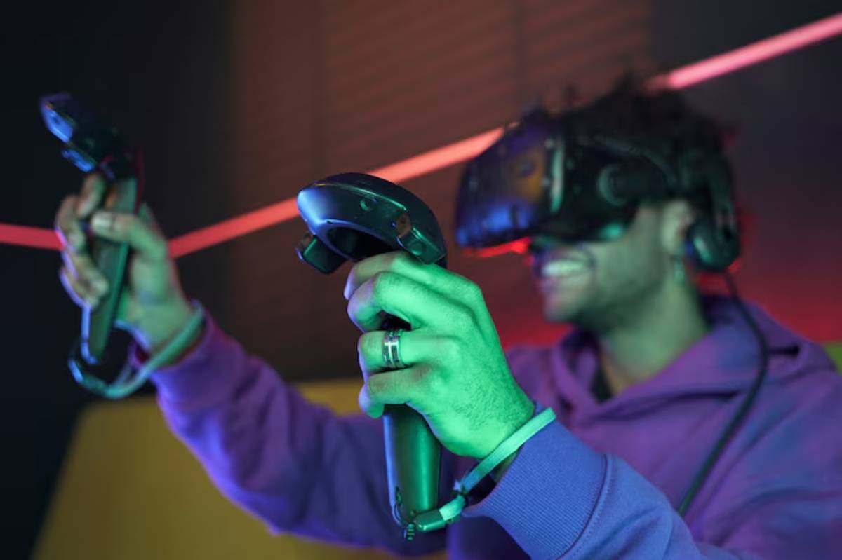 A person wearing a VR headset holds two virtual reality controllers, surrounded by colorful lighting.