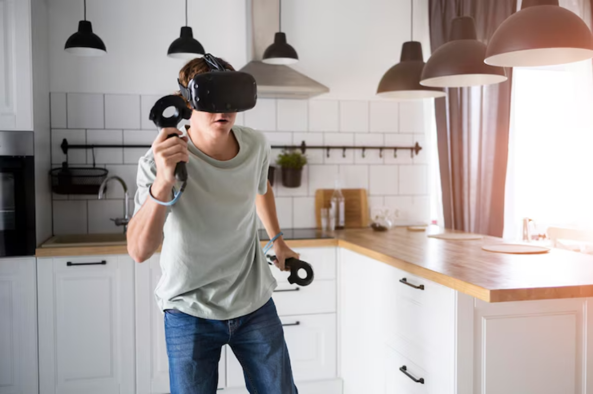 A person wearing a VR headset holds controllers while standing in a bright, modern kitchen with wooden countertops and pendant lights.