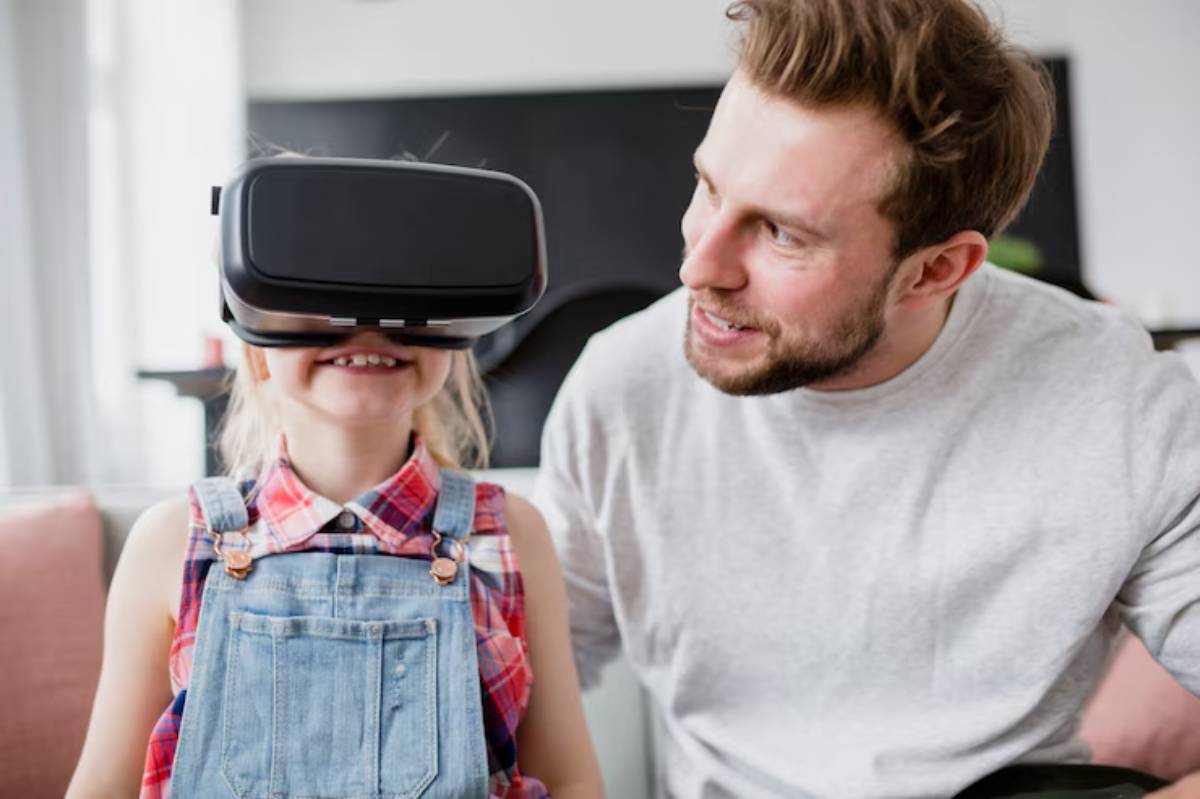 A young girl wearing a VR headset smiles excitedly while seated beside an adult in a bright, modern living room.