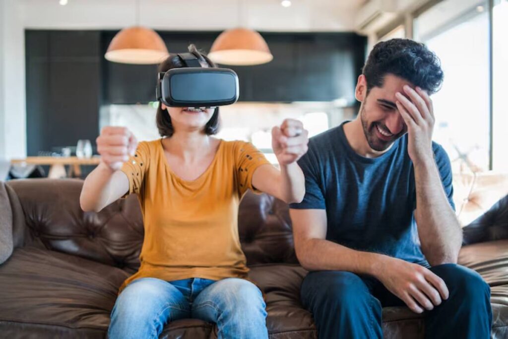 A person wearing a VR headset engages intensely on a sofa, while another individual beside them appears distressed or distracted.