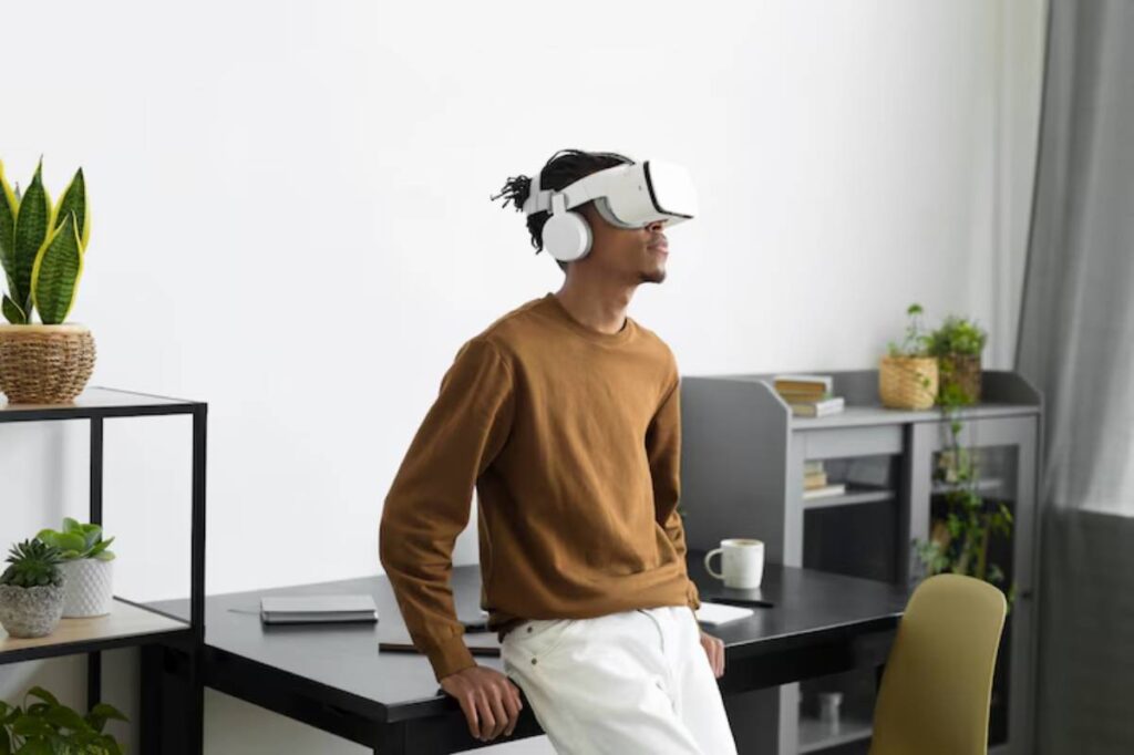 A person wearing a VR headset stands in a modern, minimalist workspace adorned with plants and a desk.