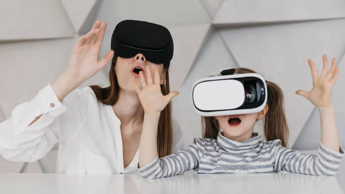 A child wearing a virtual reality headset expresses excitement while sitting at a table with a person beside her.