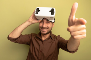A person wearing a virtual reality headset points towards the viewer, with a plain green background.