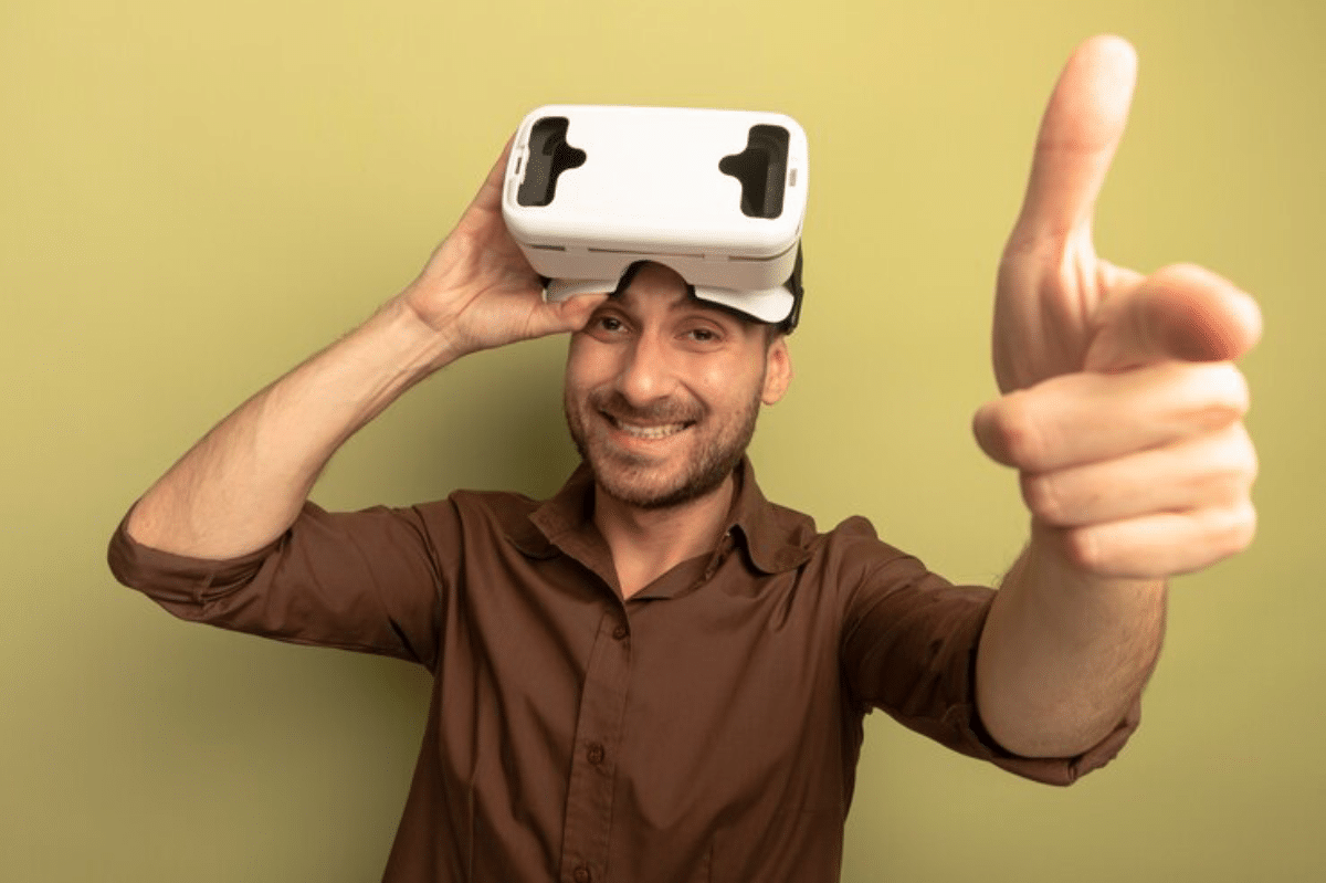 A person wearing a virtual reality headset points towards the viewer, with a plain green background.