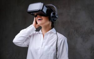 A person wearing a VR headset and headphones stands against a textured gray background, engaged in a virtual experience.