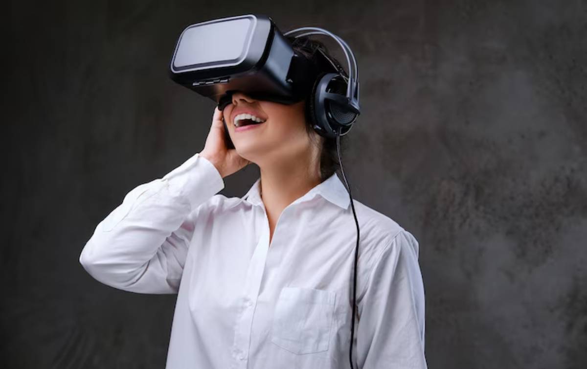 A person wearing a VR headset and headphones stands against a textured gray background, engaged in a virtual experience.
