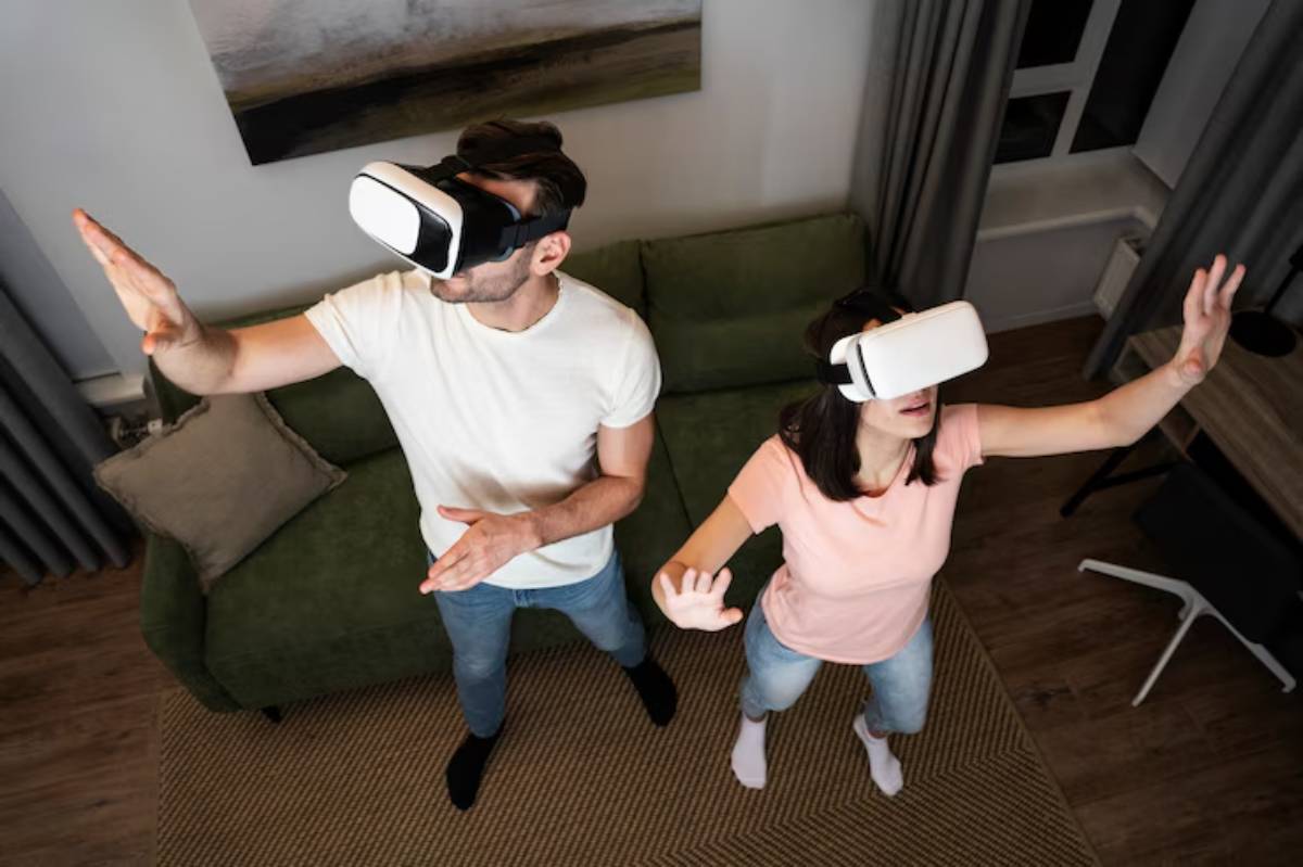 A man and a woman, both wearing VR headsets, are interacting energetically in a cozy living room with a green sofa.