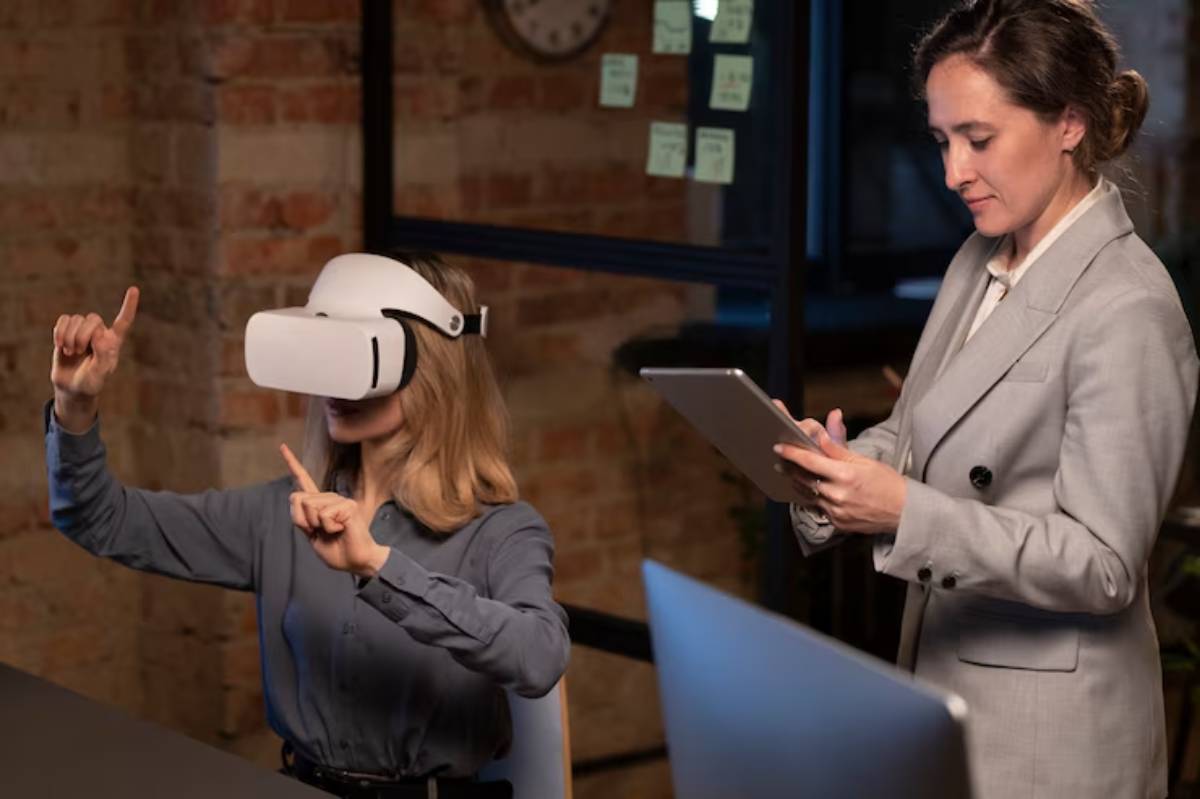 A woman wearing a VR headset gestures with her hands, while another woman in business attire observes and takes notes on a tablet.