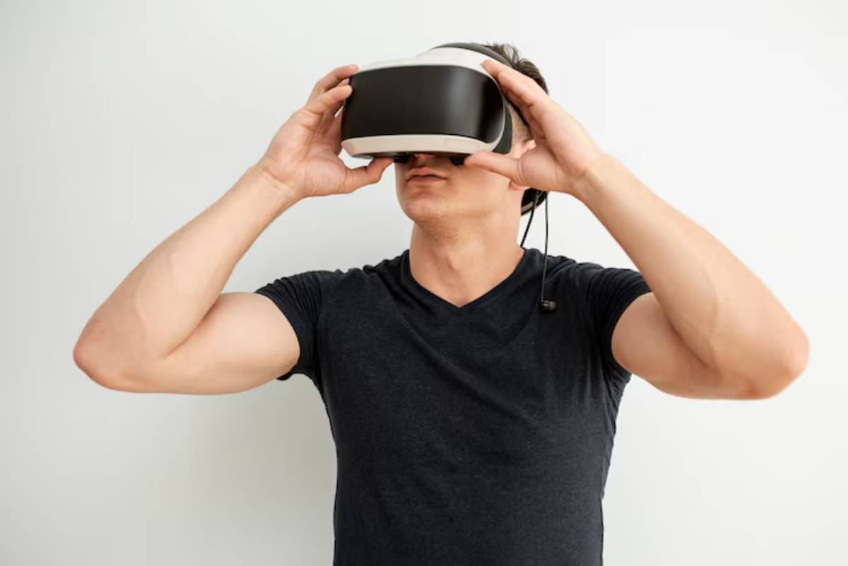 A man wearing a virtual reality headset stands against a plain white wall, engaged in an immersive gaming experience.