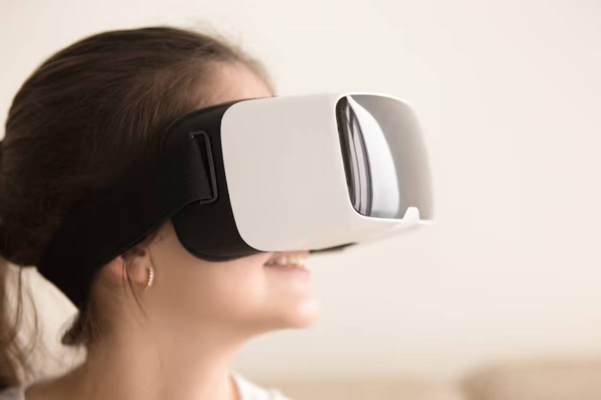 A person wearing a white VR headset, seated in a light-colored room, appears engaged in a virtual experience.
