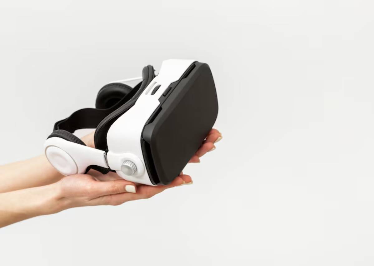A person holds a sleek, white virtual reality headset, ready for immersive experiences, against a minimalist gray background.