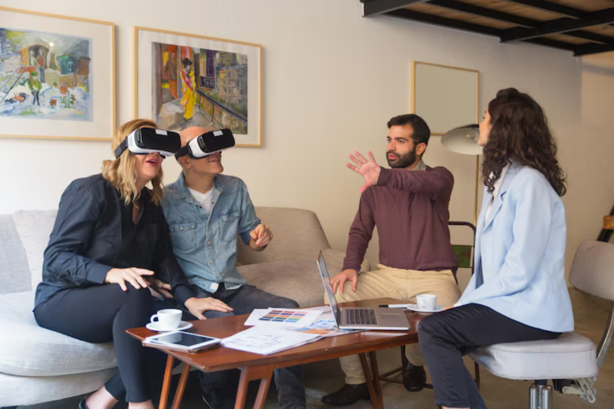 A group of four people engaged in a discussion about virtual reality, with a laptop and sketches on a coffee table in a cozy setting.
