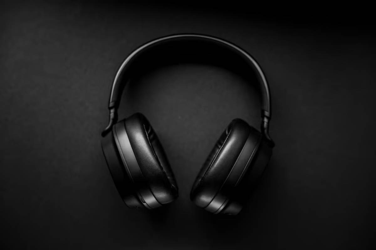 A pair of sleek black headphones positioned on a dark surface, showcasing their modern design and padded ear cups.