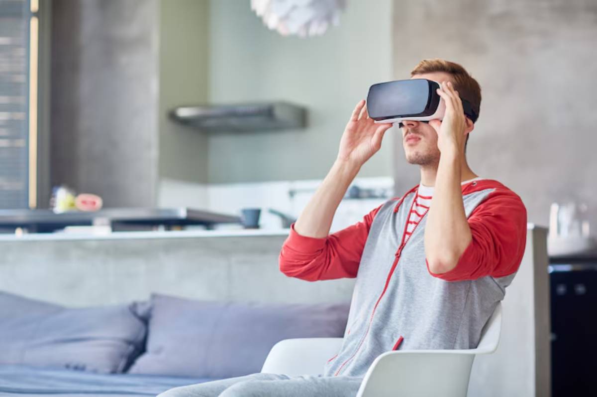 A person wearing a virtual reality headset sits casually in a bright room, engaging with immersive technology.
